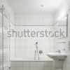 stock-photo-white-tiled-bathroom-with-toilet-bathtub-sink-and-mirror-124309912
